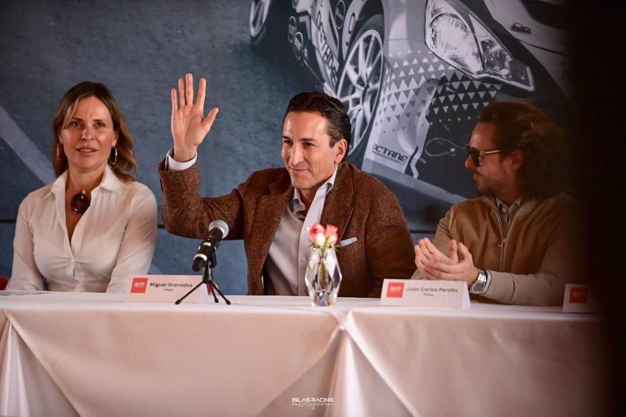 Un hombre y dos mujeres están sentados en una mesa con un micrófono.