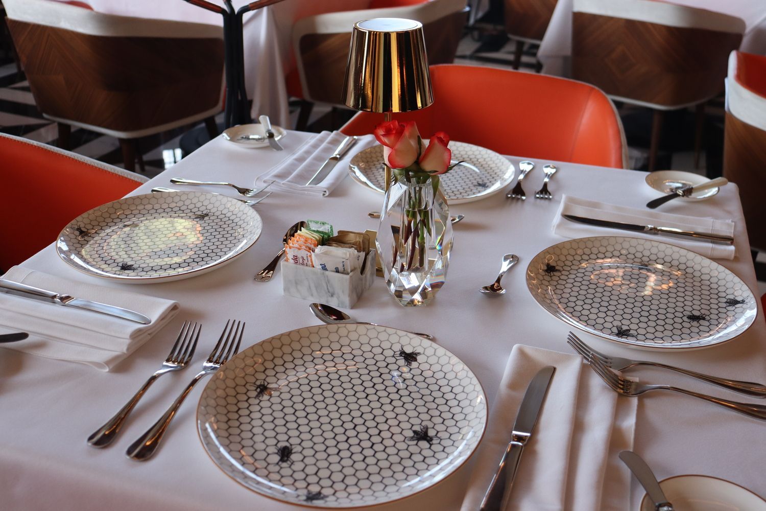 Una mesa puesta con platos, utensilios y un jarrón con flores.