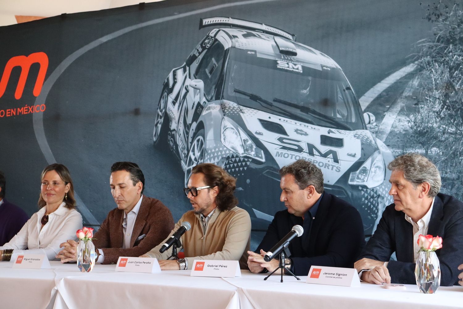 Un grupo de personas sentadas en una mesa con micrófonos.
