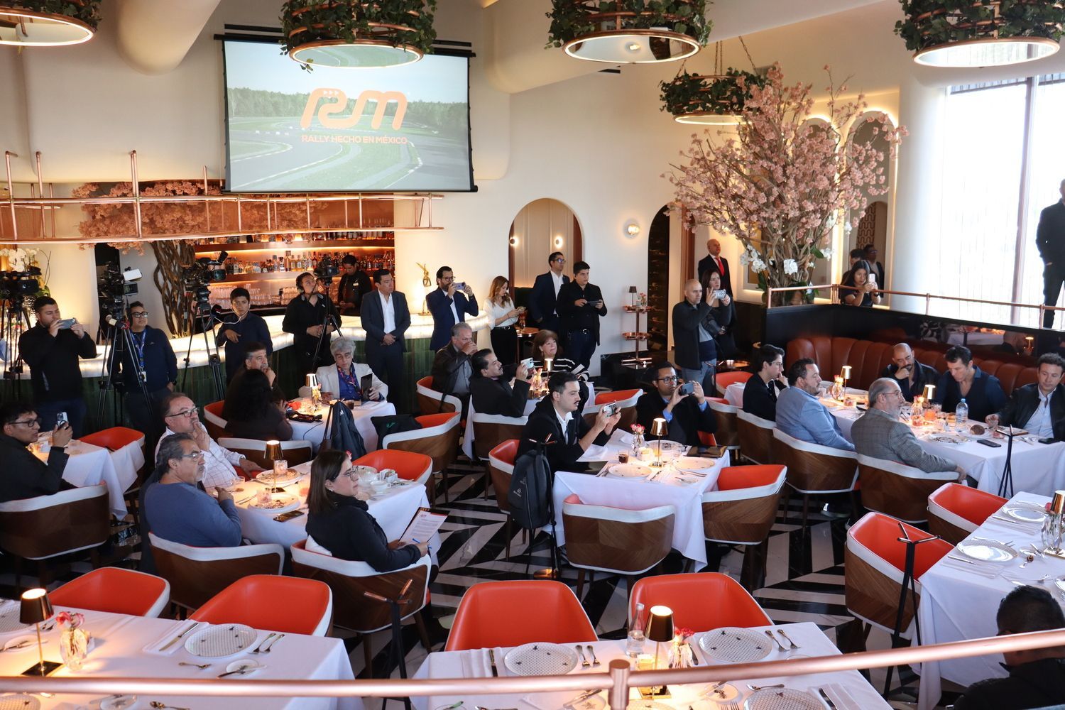 Un grupo grande de personas están sentadas en las mesas de un restaurante.