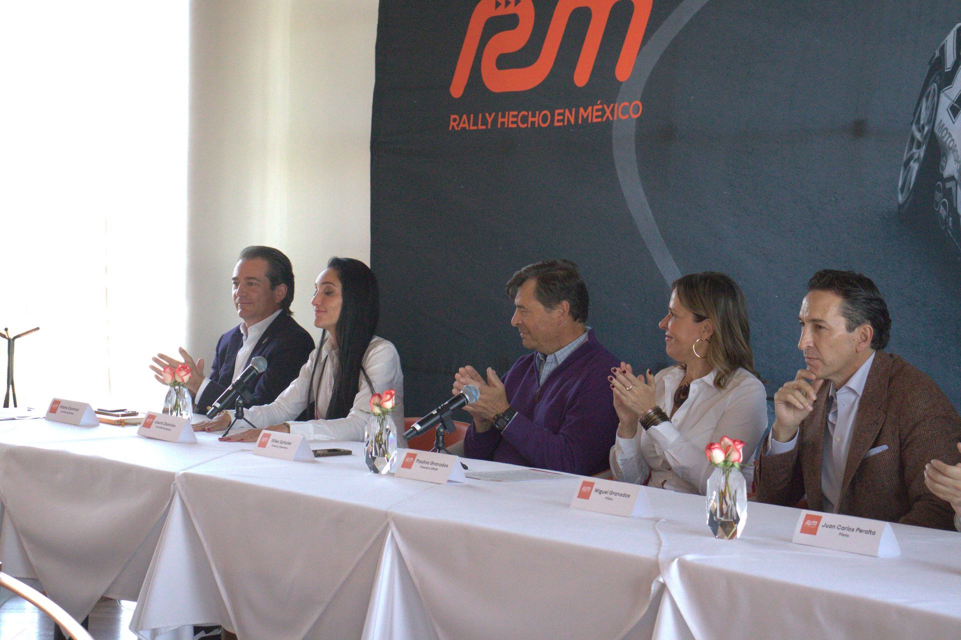 Un grupo de personas está sentado en una mesa frente a un cartel que dice manifestación.