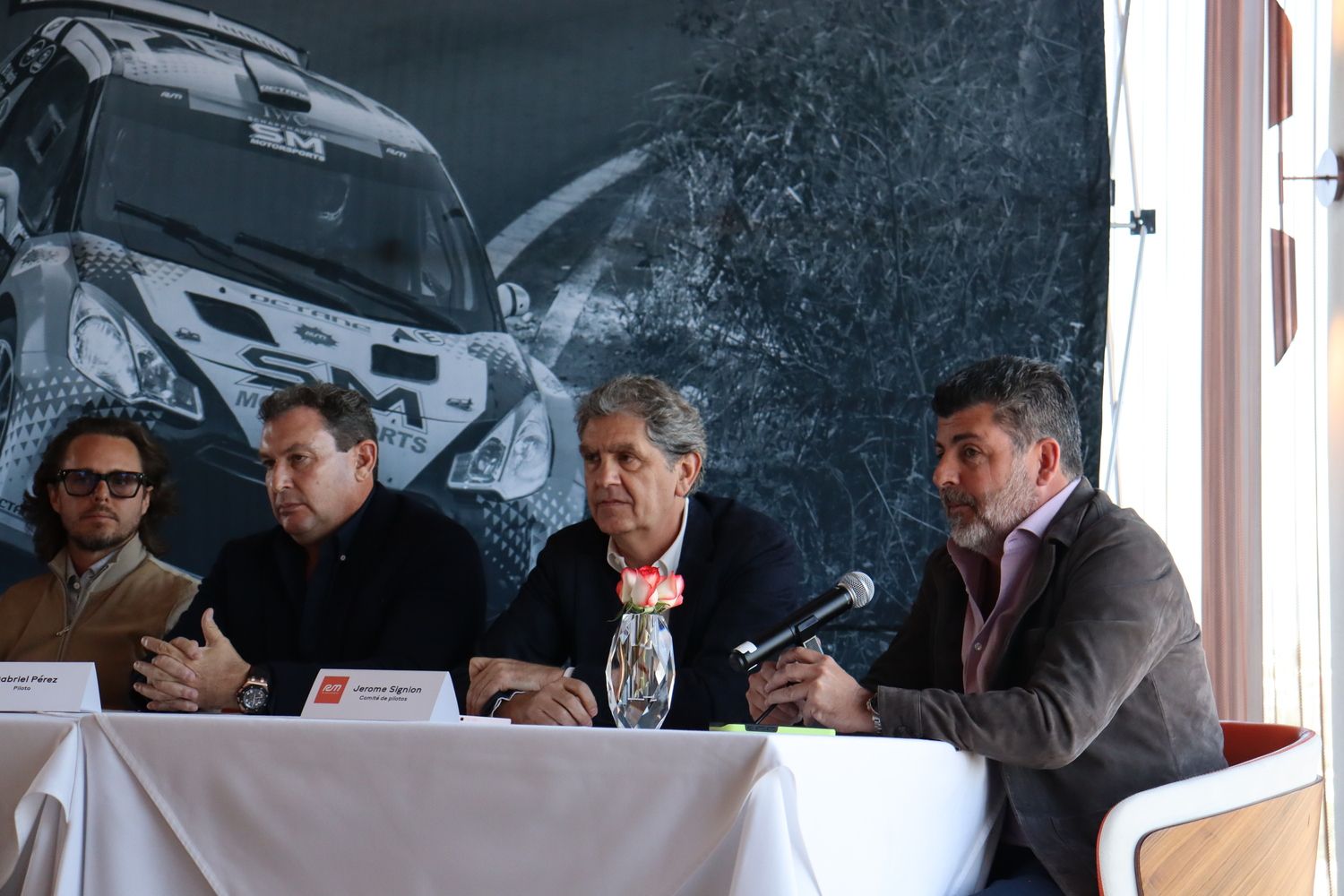 Un grupo de hombres está sentado en una mesa con un micrófono.