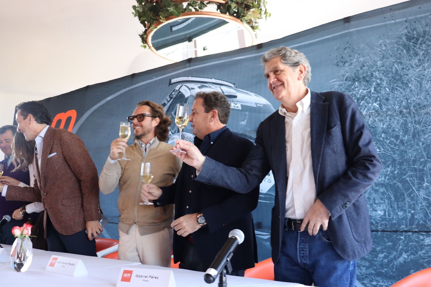 Un grupo de hombres están de pie alrededor de una mesa brindando con copas de champán.