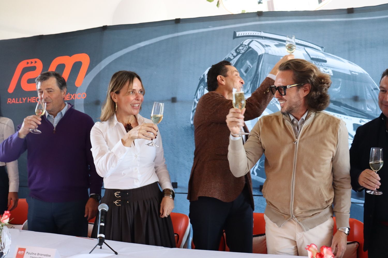 Un grupo de personas están de pie alrededor de una mesa brindando con copas de champán.