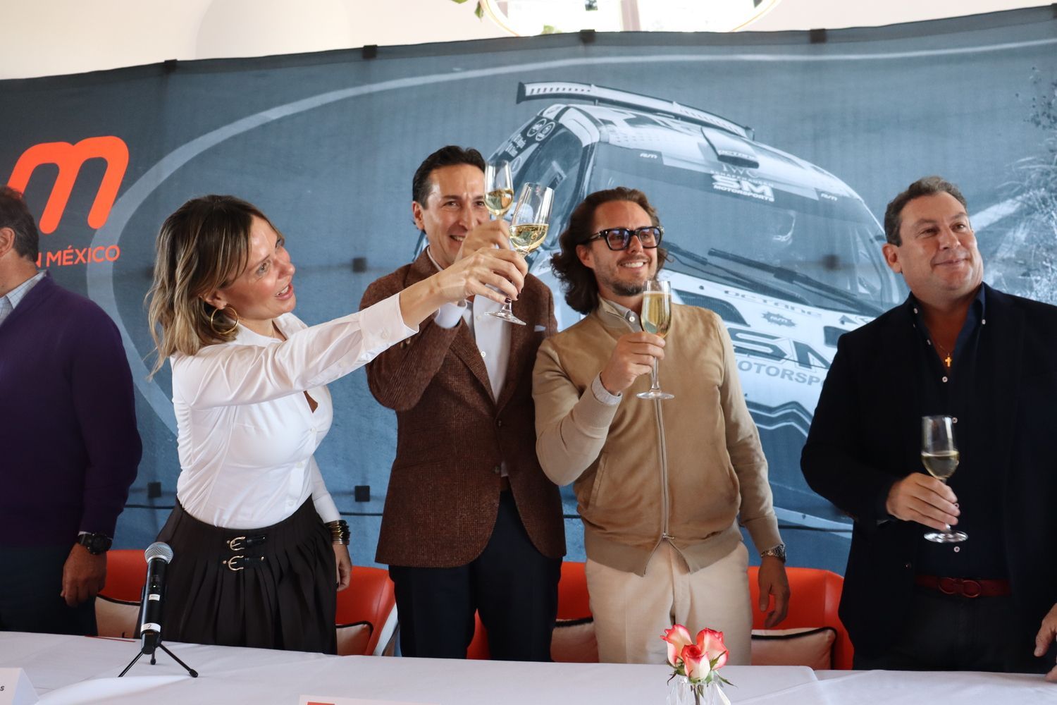 Un grupo de personas están de pie alrededor de una mesa brindando con copas de vino.
