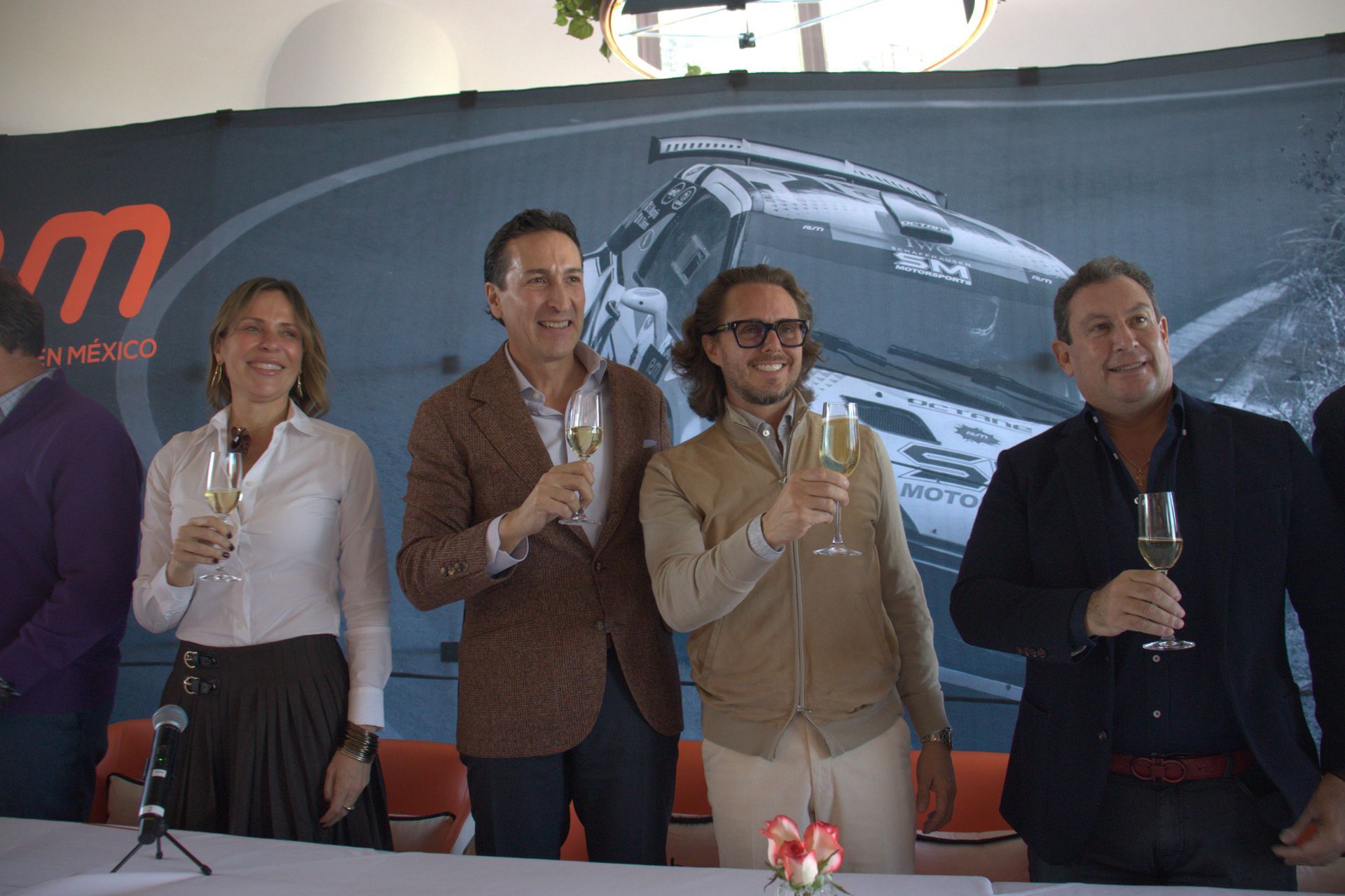 Un grupo de personas están de pie alrededor de una mesa sosteniendo copas de champán.