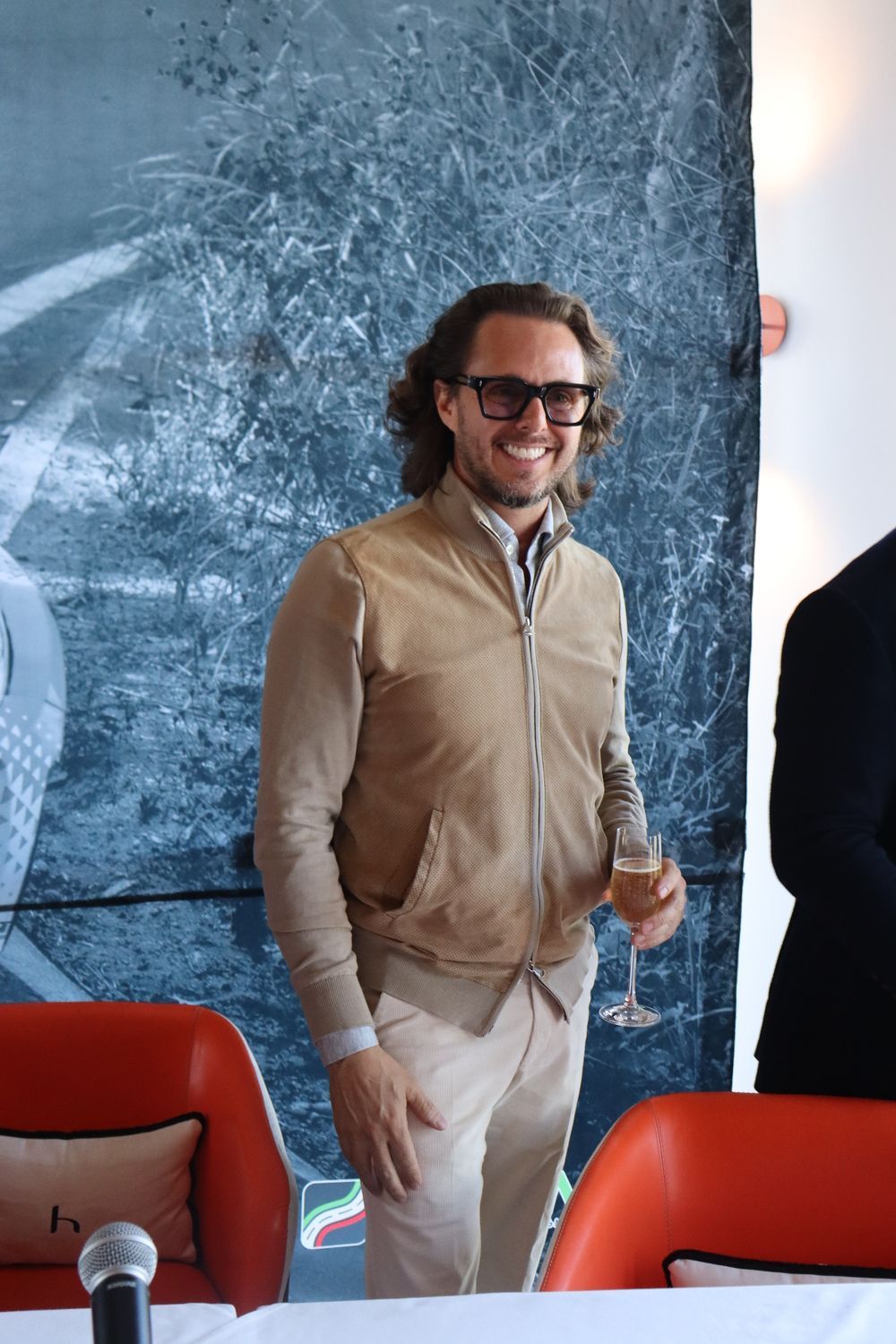 Un hombre está de pie frente a una mesa sosteniendo una copa de vino.