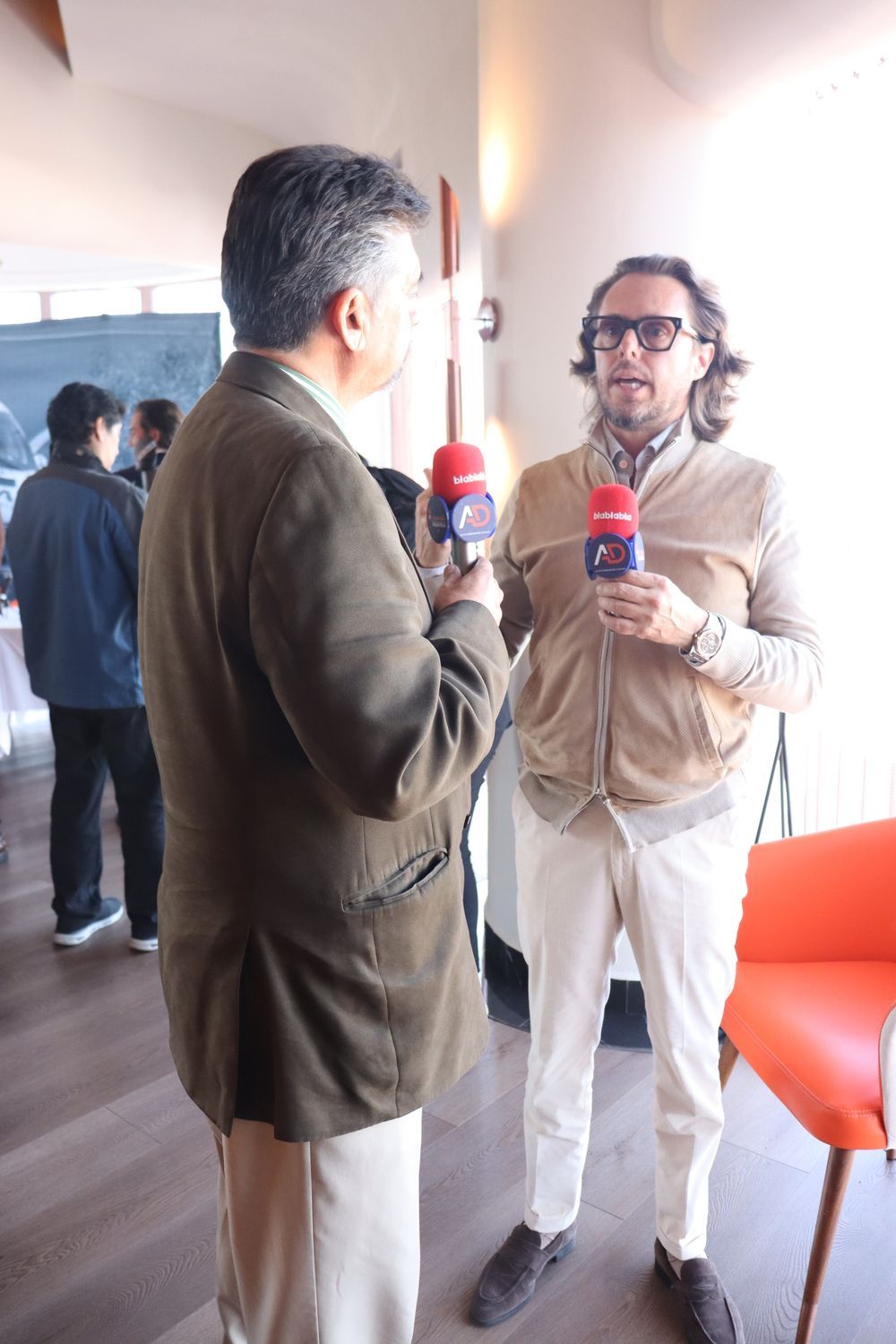 Dos hombres sostienen micrófonos y hablan entre sí.