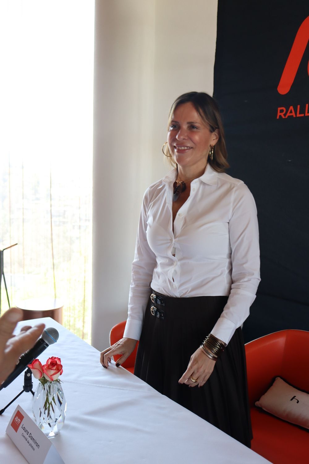 Una mujer con una camisa blanca está parada frente a un micrófono.