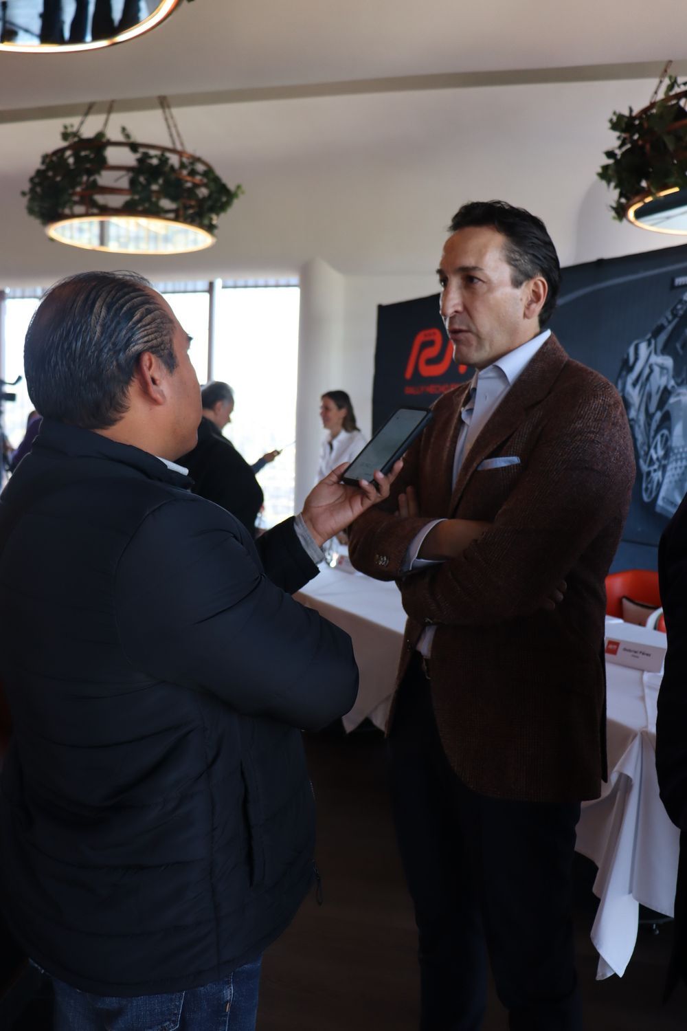Un hombre con traje está hablando con otro hombre mientras sostiene un micrófono.