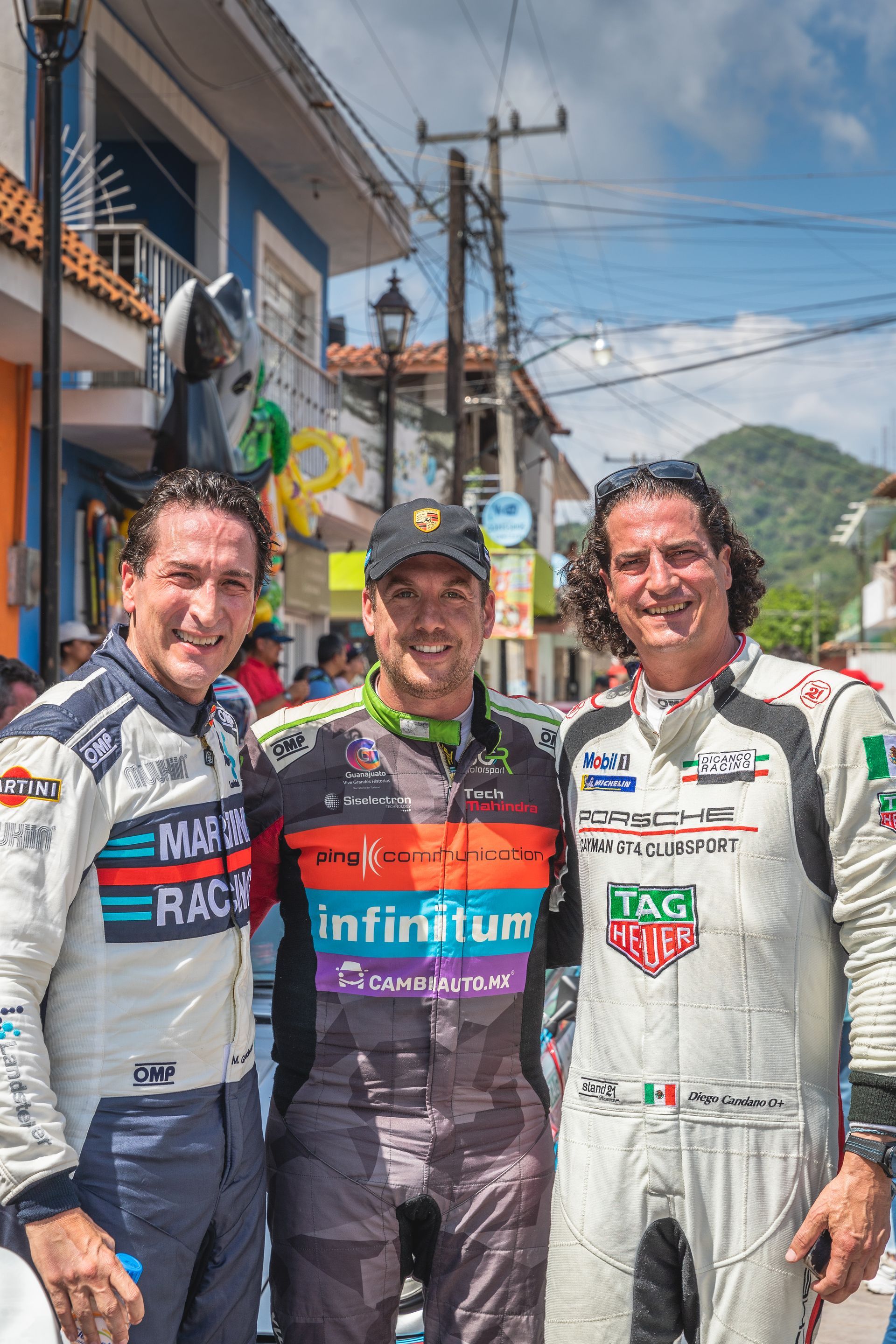 Tres hombres vestidos de carreras posan para una fotografía delante de un edificio.