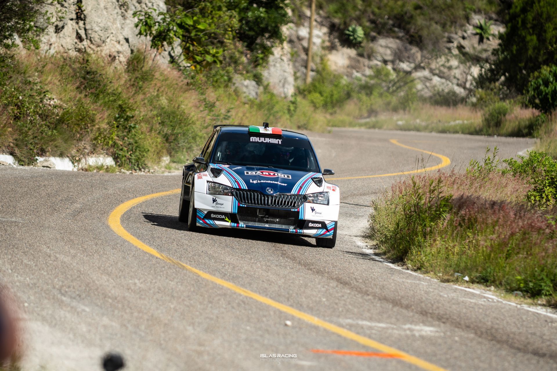Un coche de carreras azul y blanco circula por una carretera con curvas.