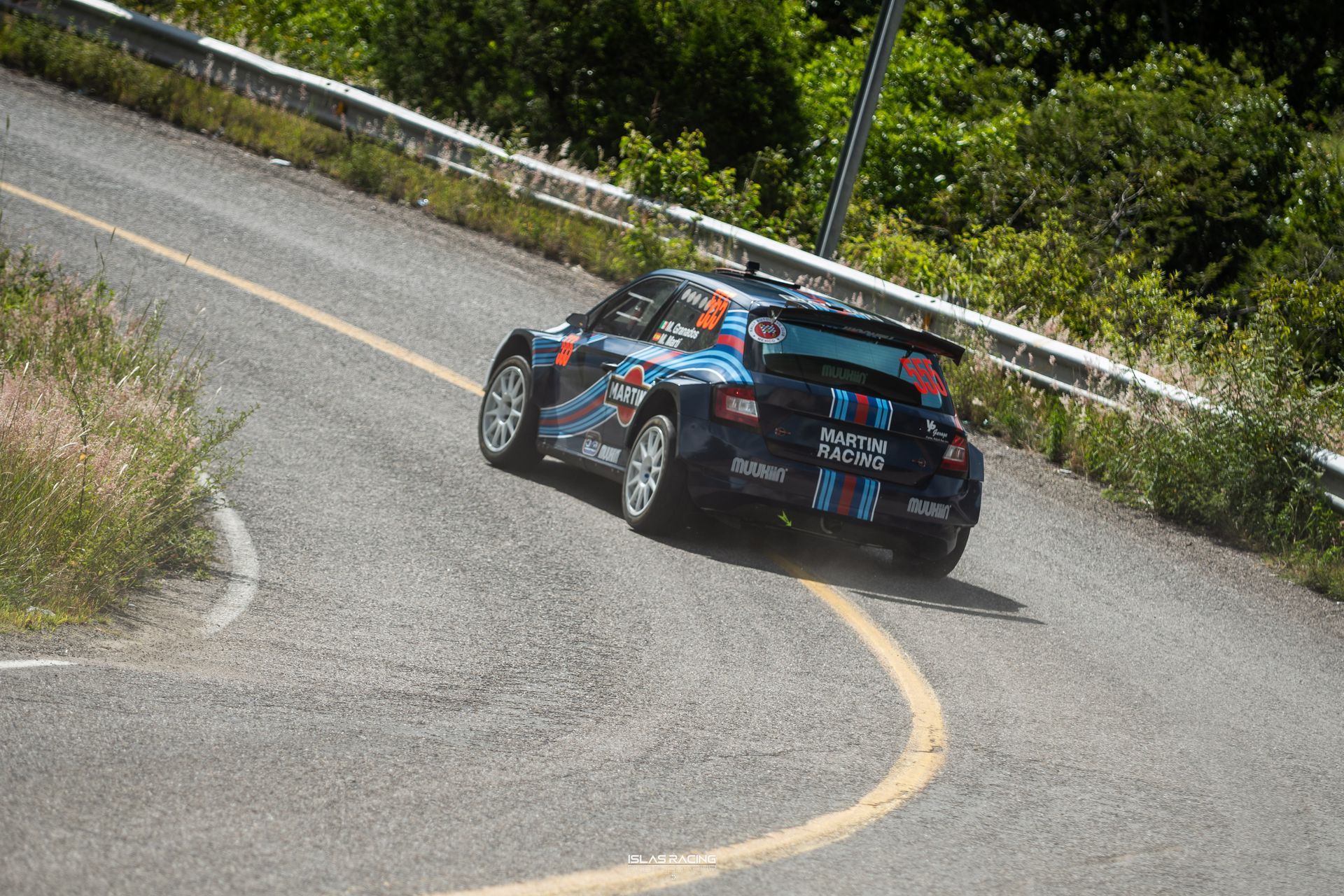 Un coche de carreras azul circula por una carretera con curvas.