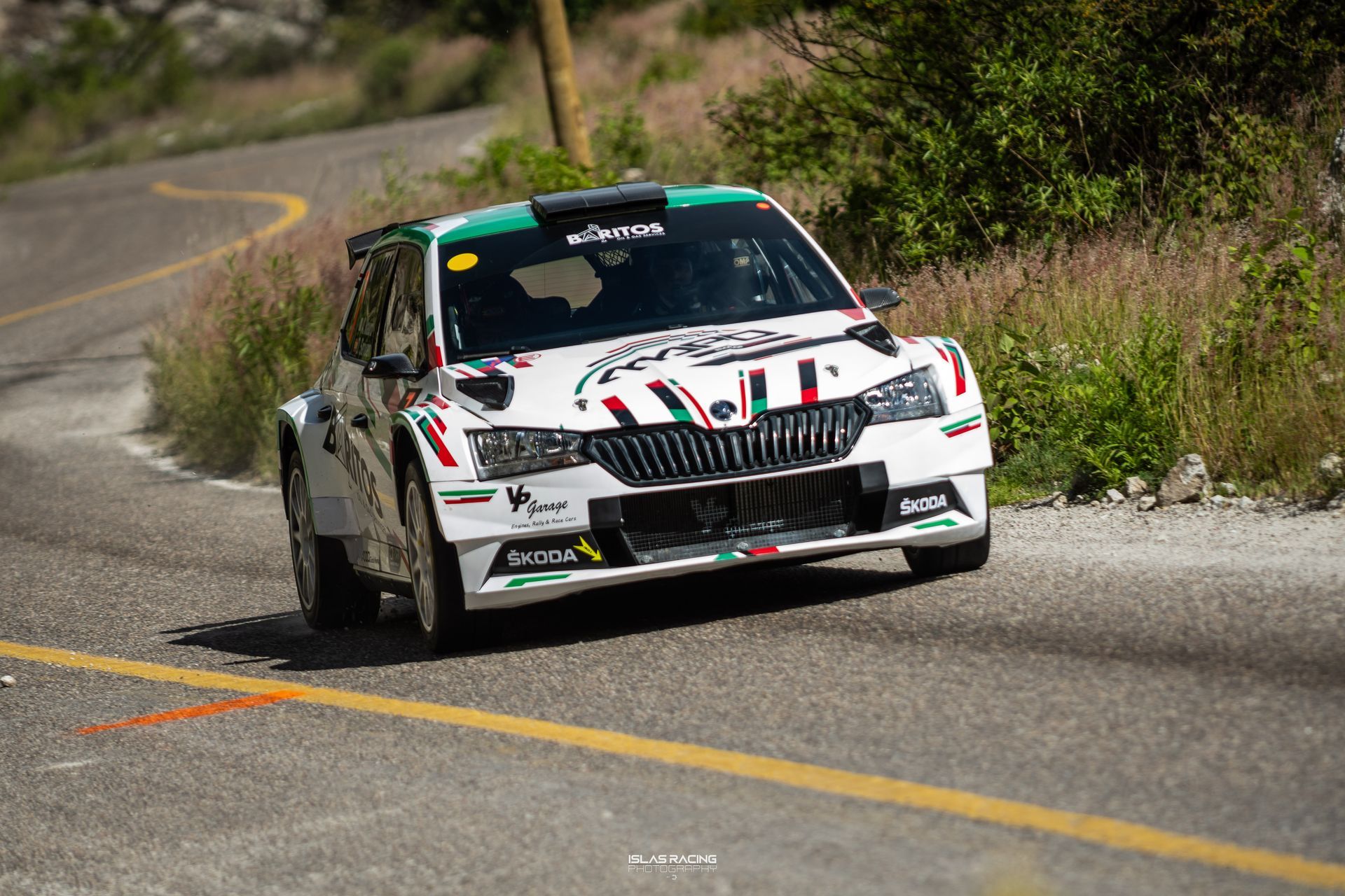 Un coche de carreras blanco y verde circula por una carretera.