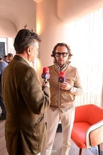 Dos hombres hablan entre sí en una habitación mientras sostienen micrófonos.