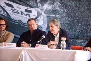 Un grupo de hombres está sentado en una mesa con micrófonos.