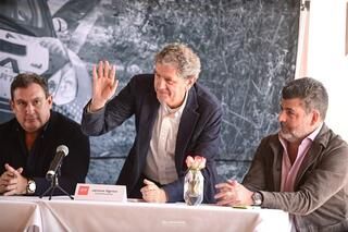 Tres hombres están sentados en una mesa con micrófonos.