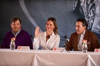 Tres personas están sentadas en una mesa con micrófonos.