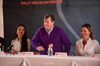 Un hombre con un suéter morado está de pie en una mesa con dos mujeres.