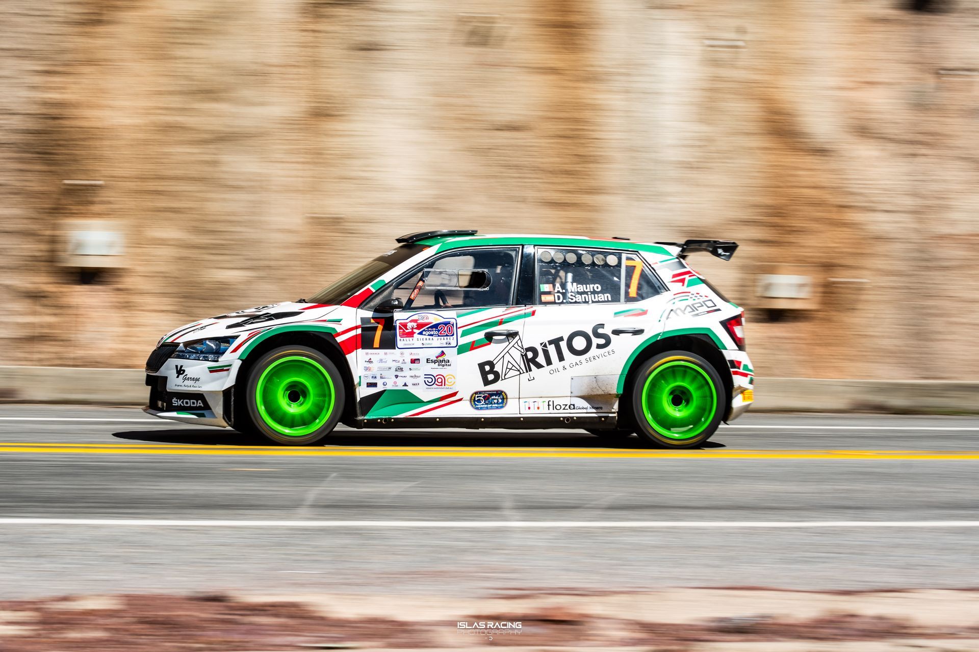 Un coche de carreras verde y blanco circula por una calle.