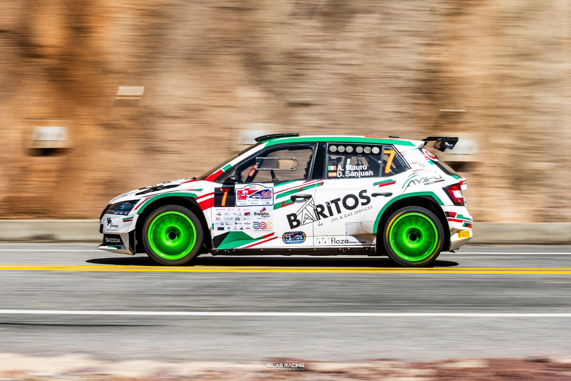 Un coche de rally blanco y verde circula por una carretera.
