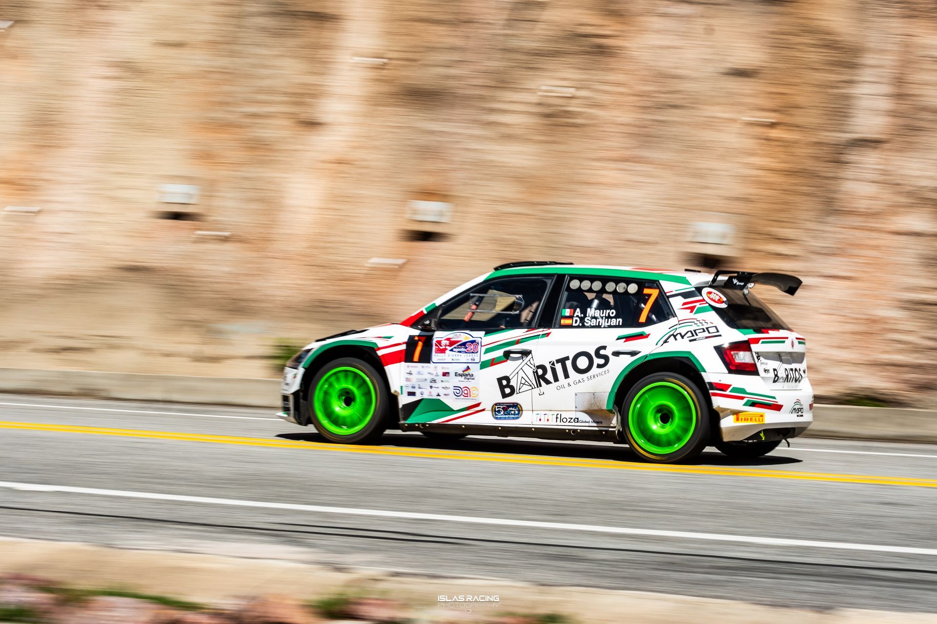 Un coche de carreras verde y blanco circula por una carretera.