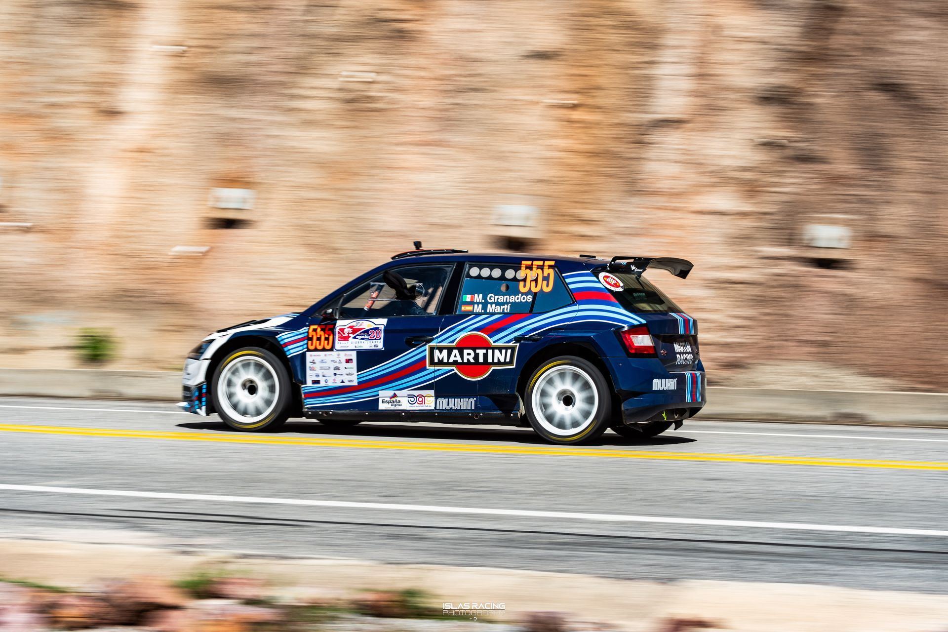 Un coche de carreras azul y blanco circula por una calle.