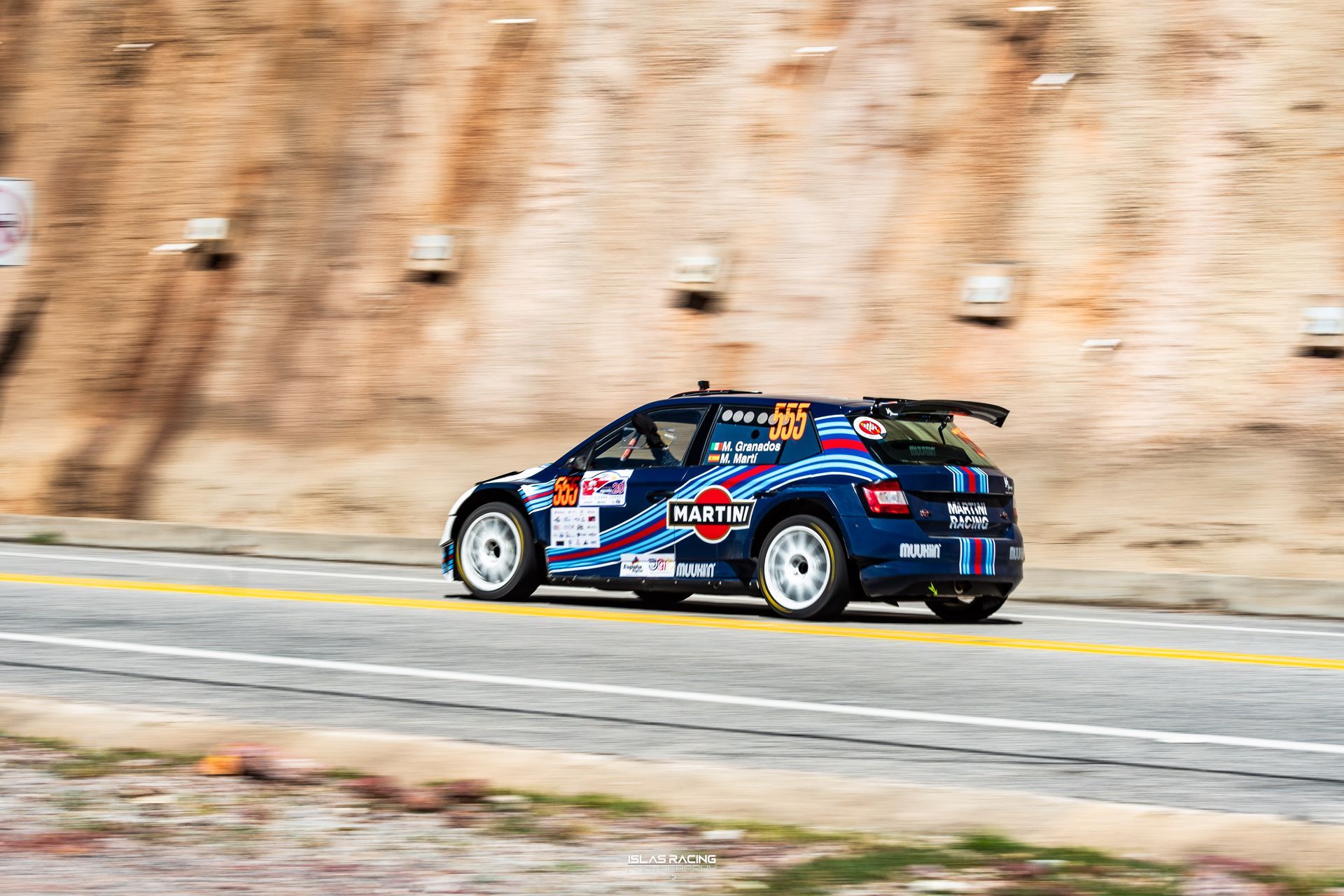Un coche de carreras azul circula por una carretera.
