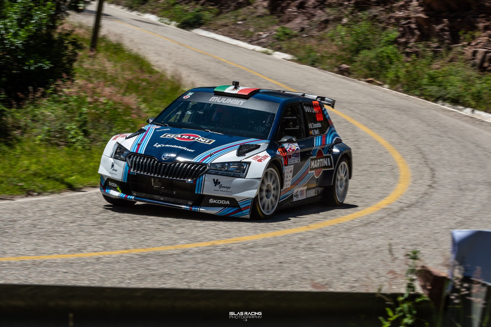 Un coche de carreras azul y blanco circula por una carretera con curvas.