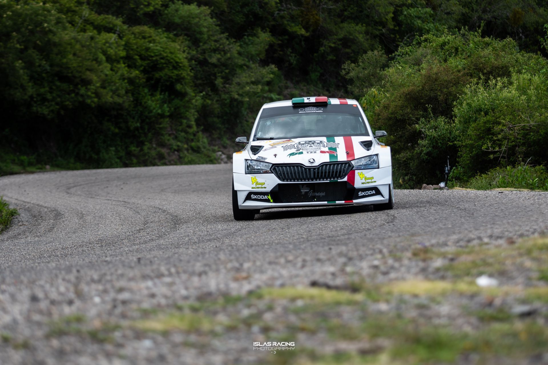Un coche de carreras blanco circula por un camino de tierra.
