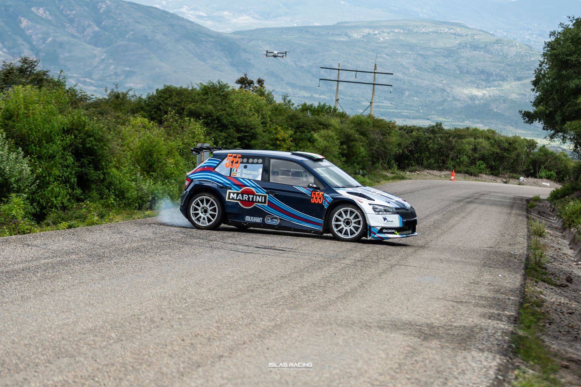 Un coche de rally circula por un camino de tierra.