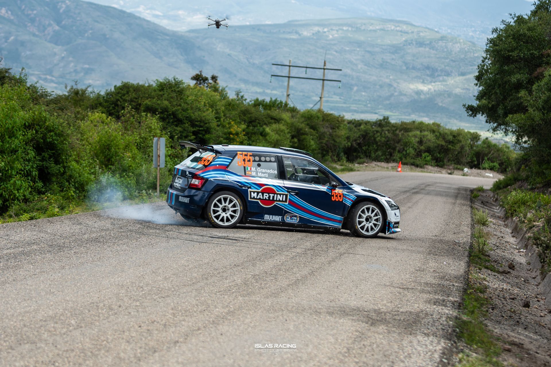 Un coche azul y blanco circula por un camino de tierra.