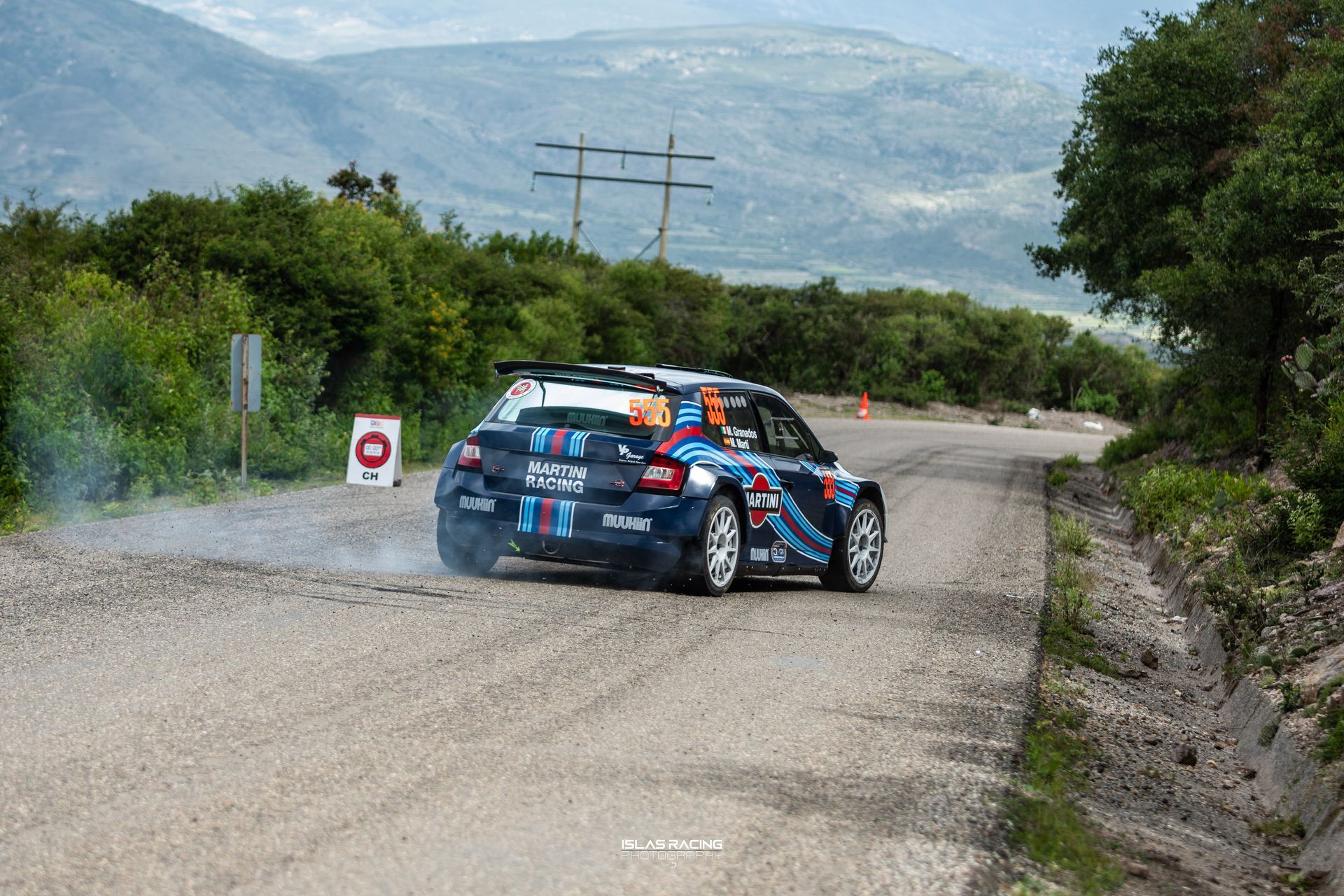 Un coche de rally circula por un camino de tierra.