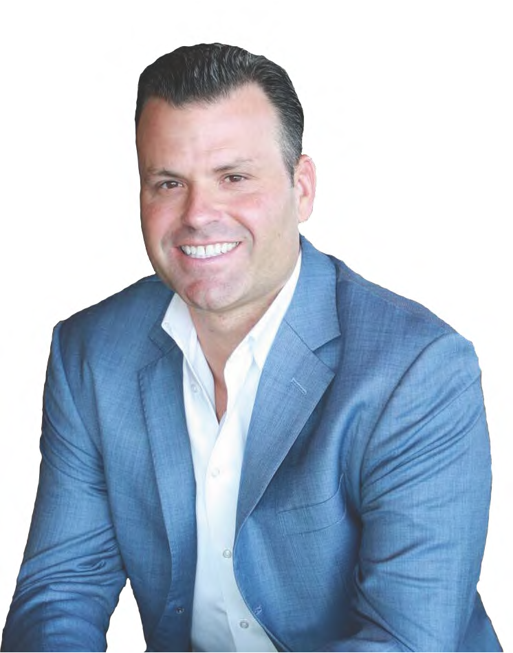 Man in a blue blazer and white shirt smiles; studio shot.