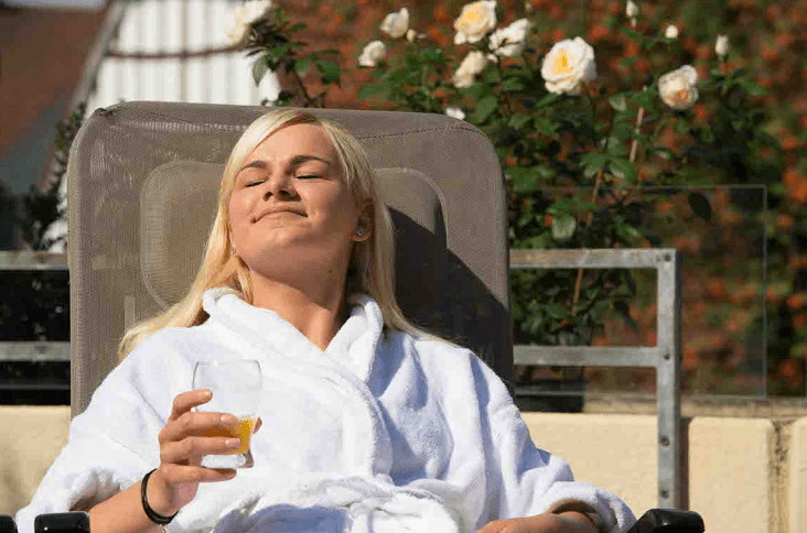 Frau sitz mit Bademantel in der Sonne