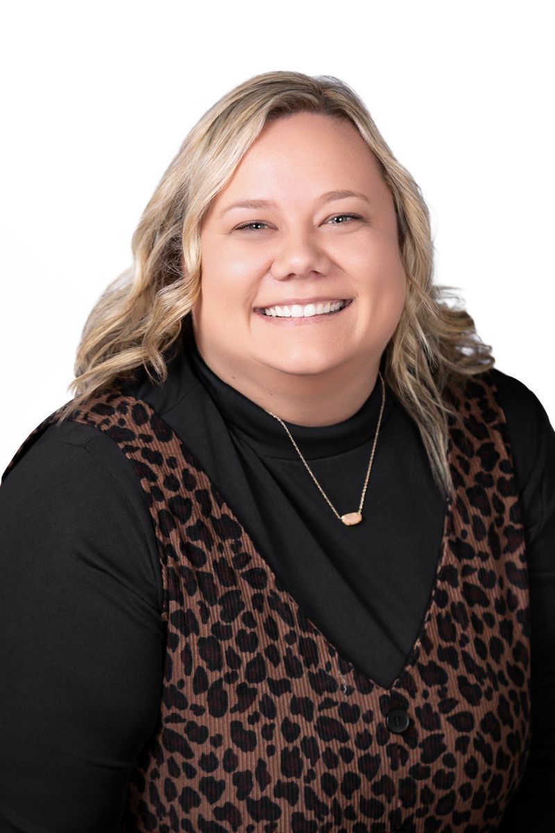 A woman in a green polka dot shirt is smiling for the camera.