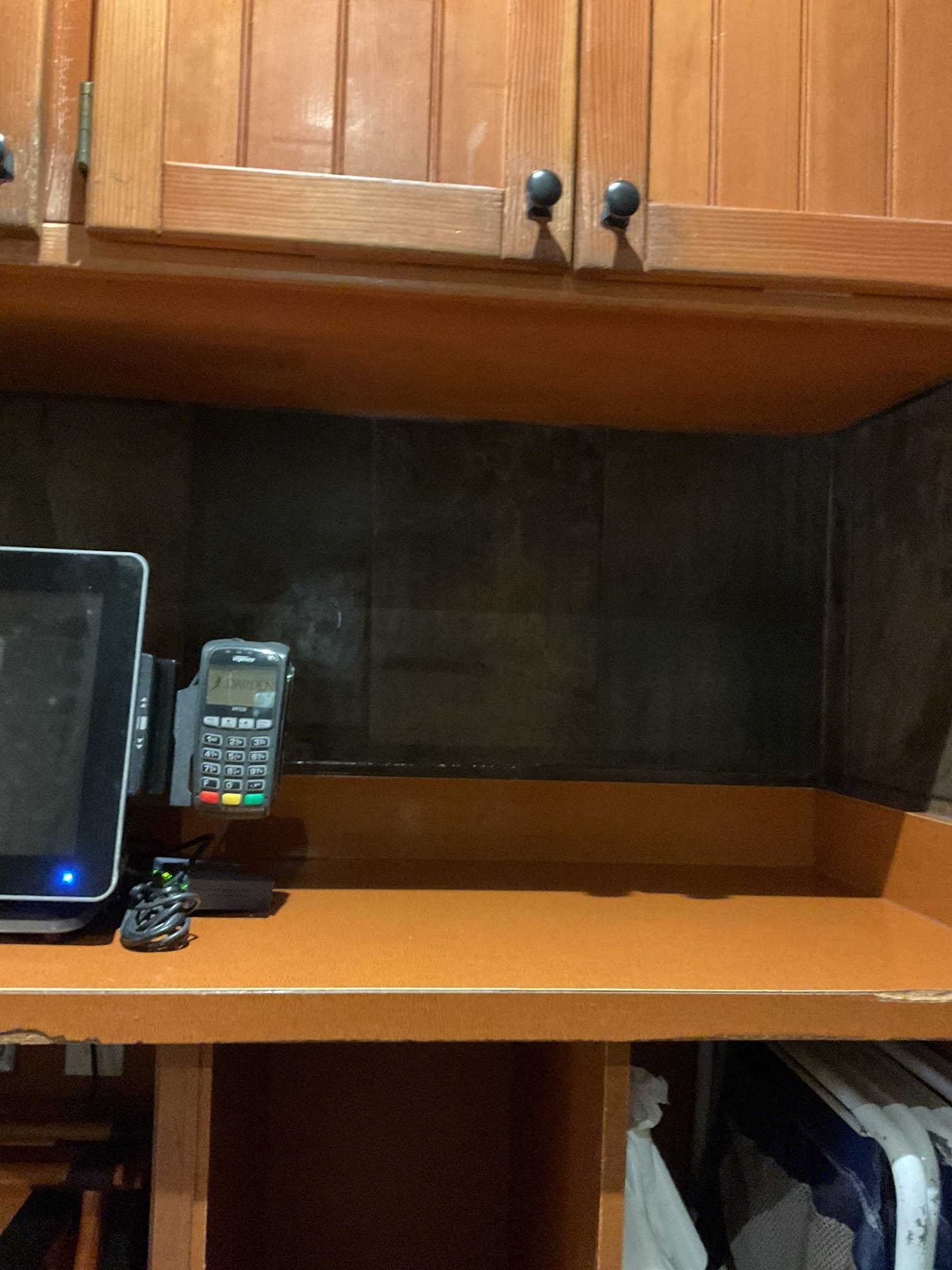 Cashier station with mounted screen, payment terminal, and cabinets.