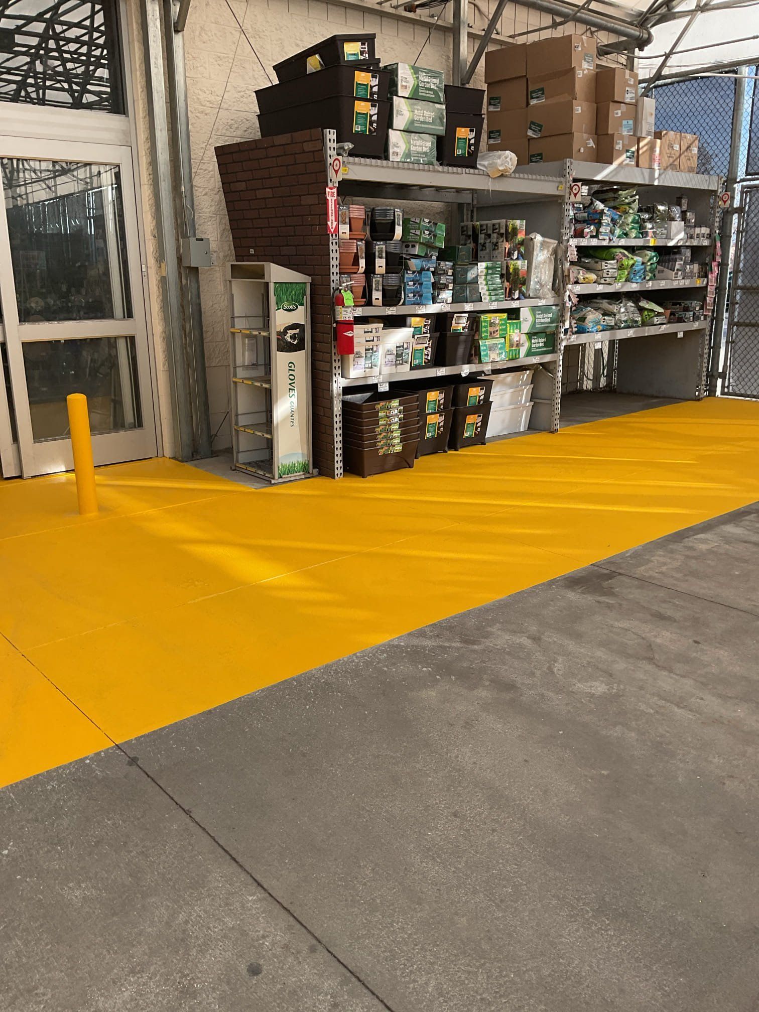 Yellow painted floor in a store, leading to shelves with items. A yellow pole on the left.