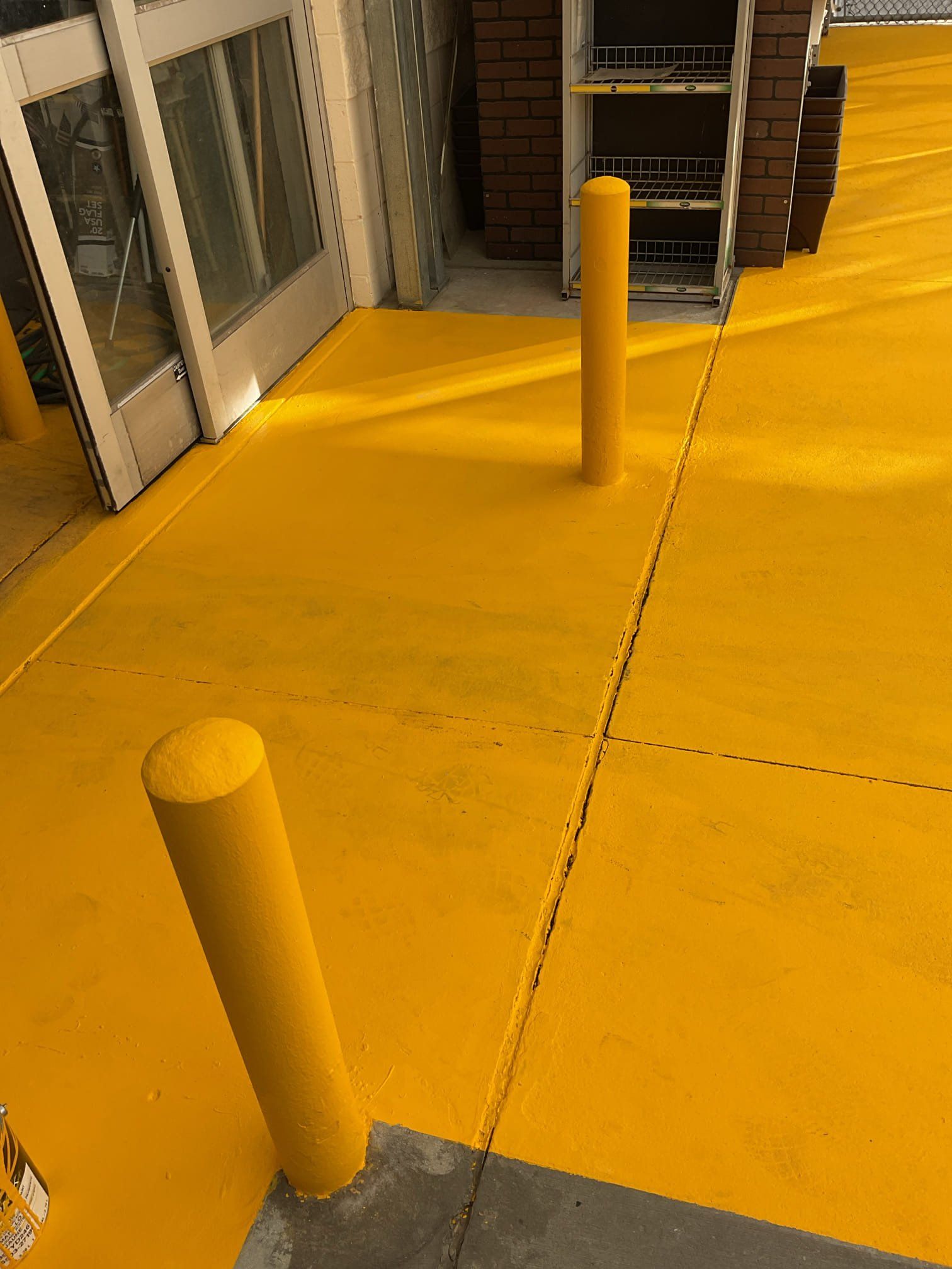 Yellow painted concrete entrance with yellow bollards.