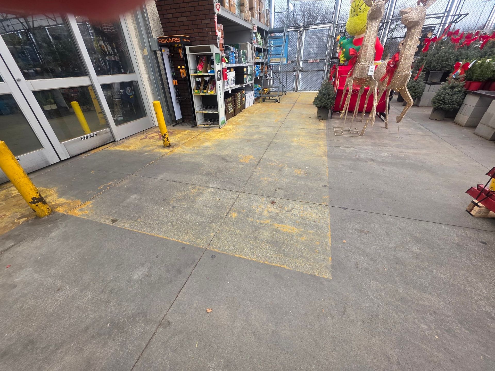 Dirty kitchen floor with a floor drain. Brown tiles, white walls, and pipes.