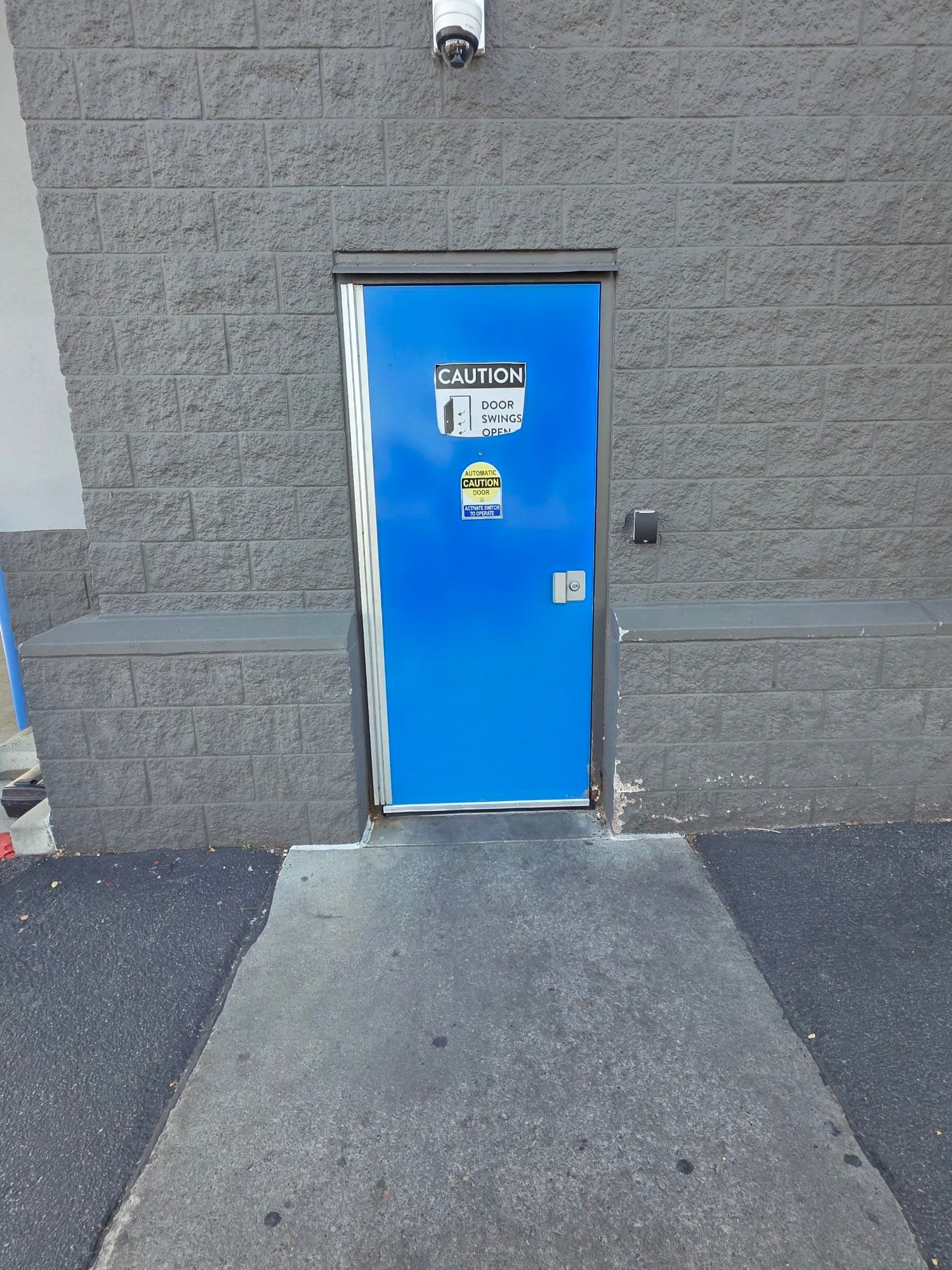 Dirty kitchen floor with a floor drain. Brown tiles, white walls, and pipes.