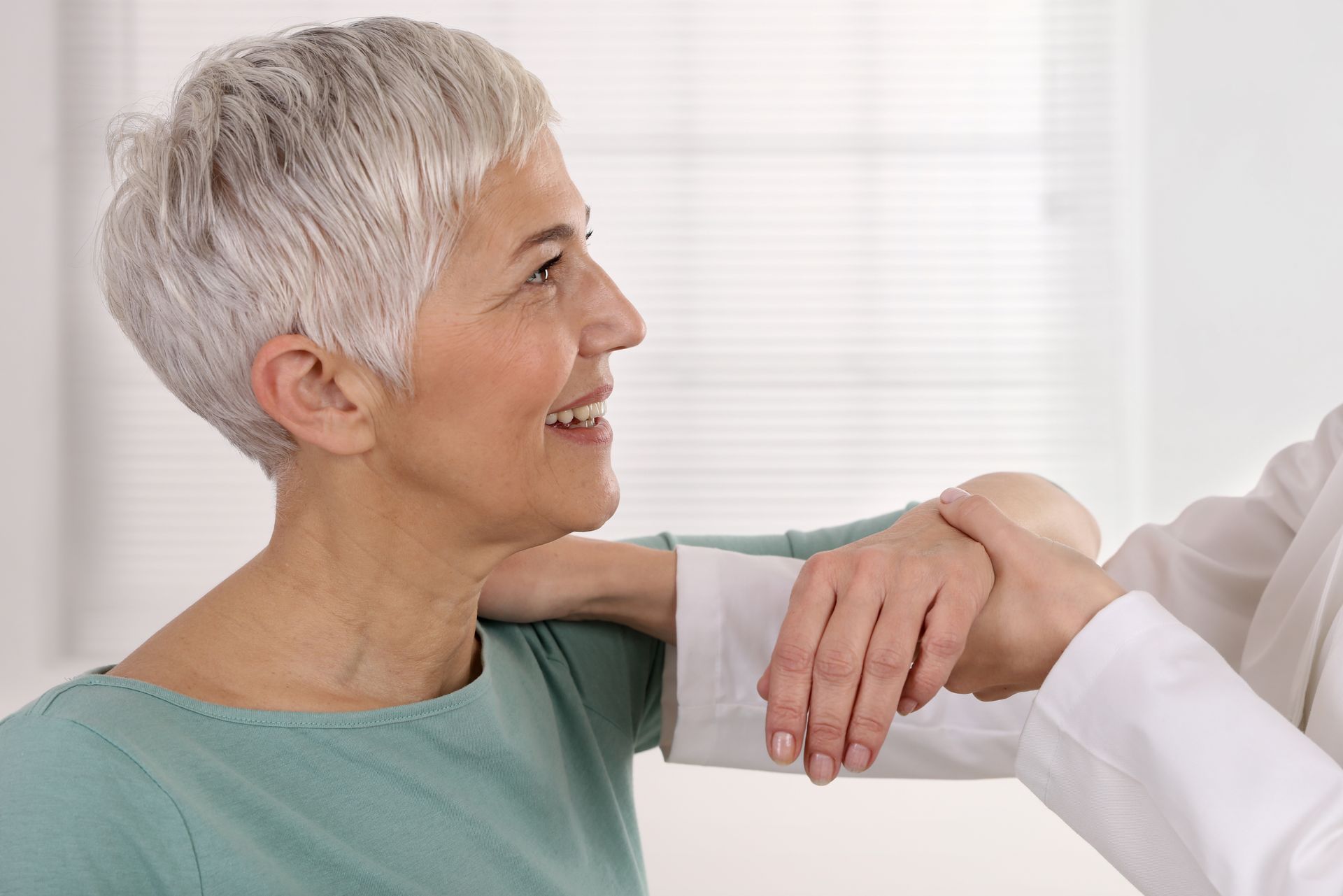 A doctor is holding the hand of an older woman.