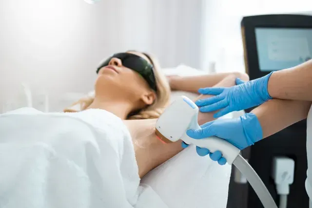 A woman is getting a laser hair removal treatment on her underarm.