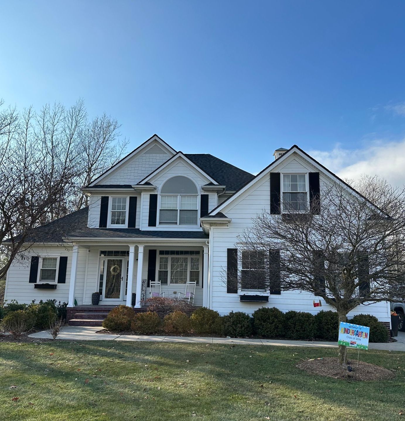 A large white house with black shutters is for sale