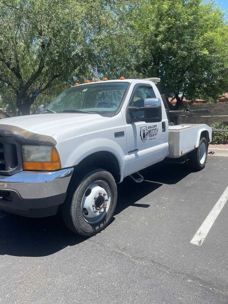 A white tow truck is parked in a parking lot.