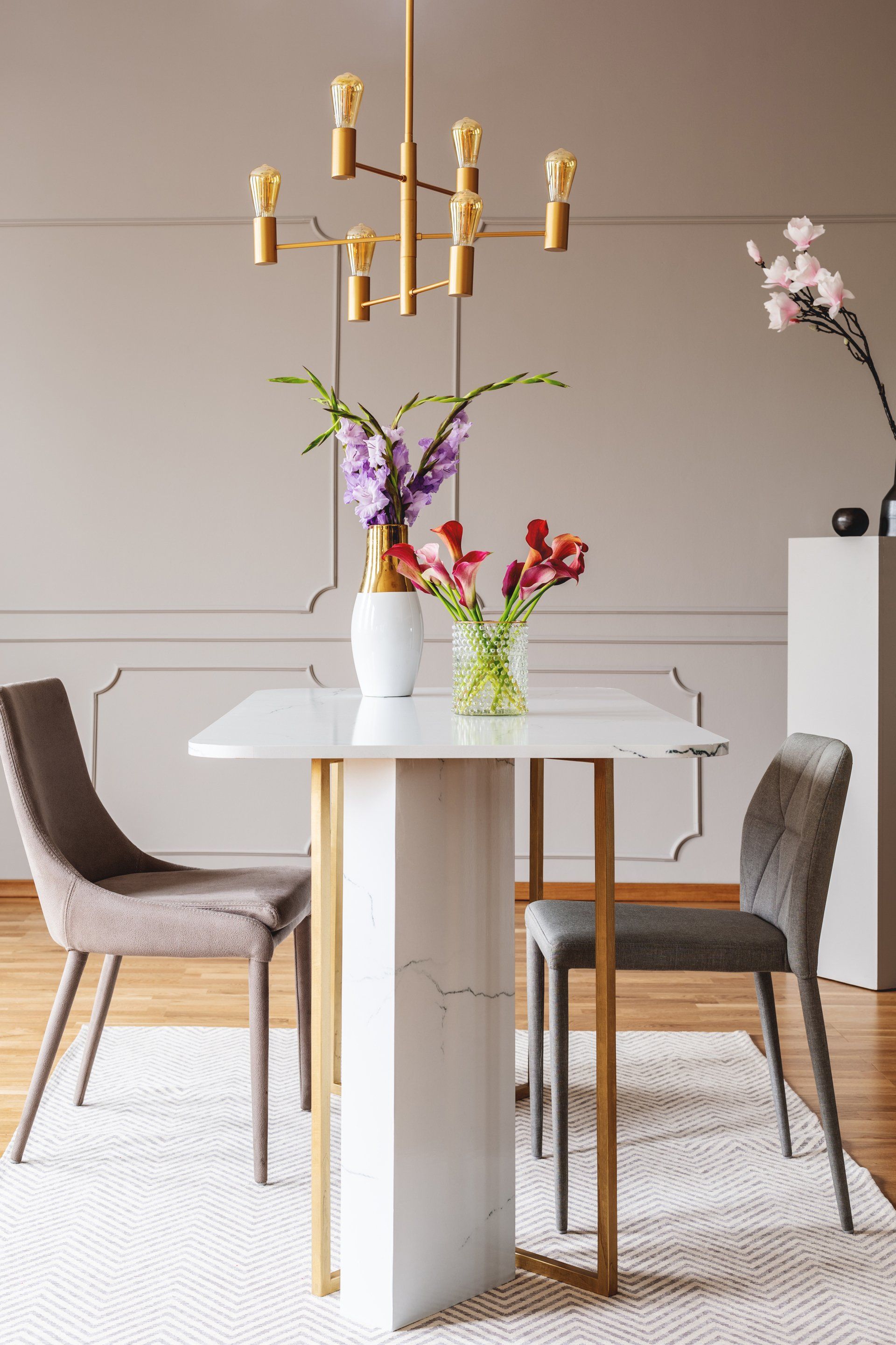 A dining room with a table and chairs and a vase of flowers on it.