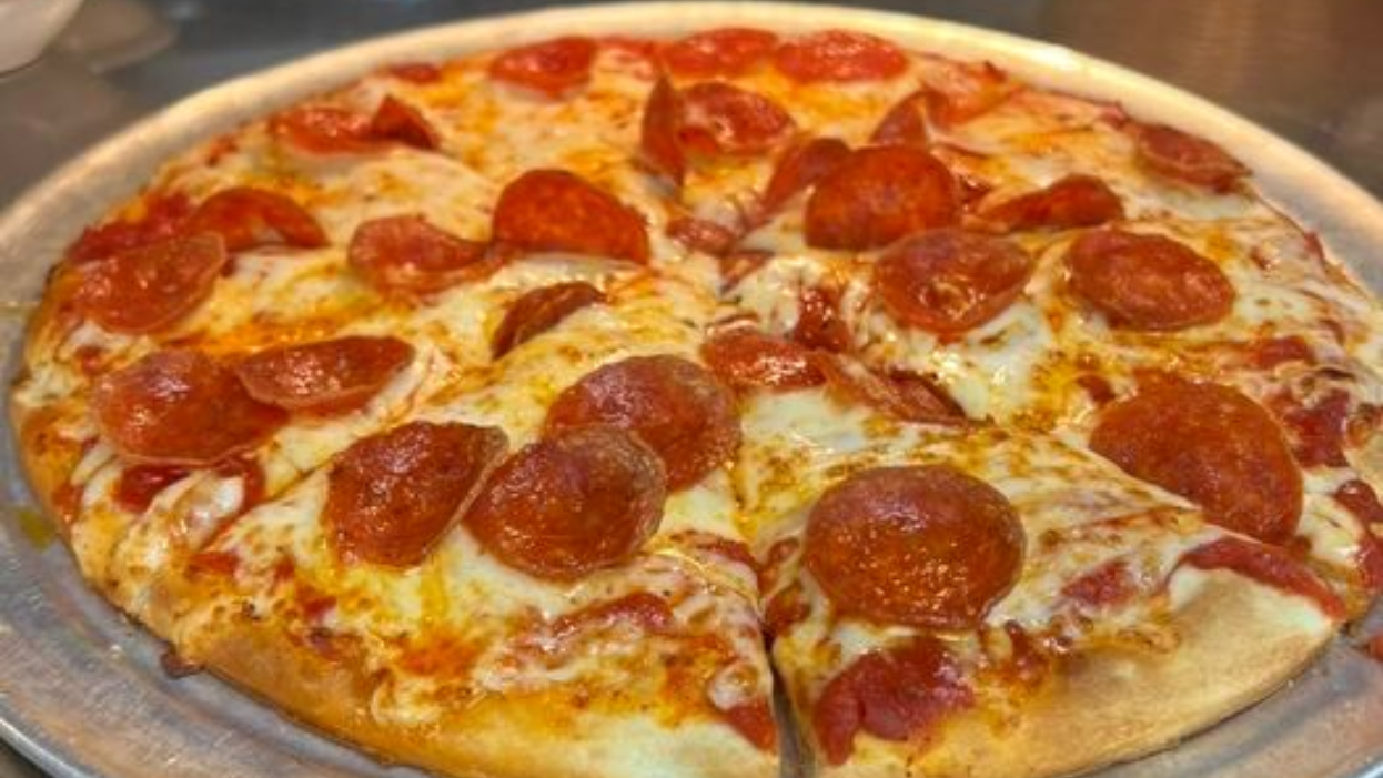 Pepperoni pizza on a metal tray, with melted cheese and red pepperoni slices.