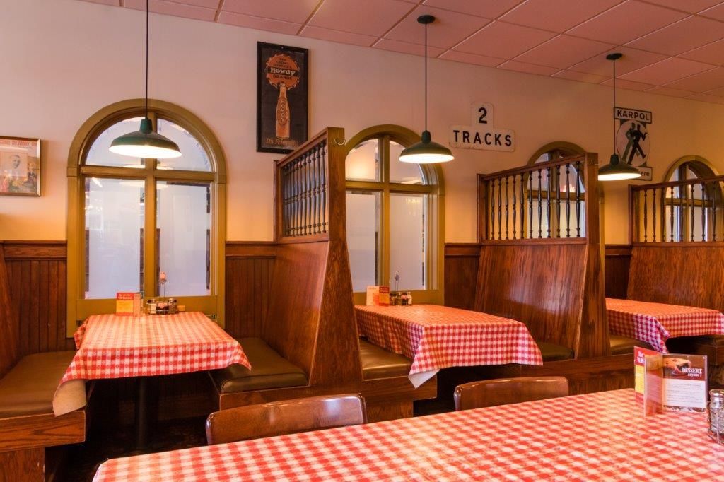 Restaurant interior with booths, red checkered tablecloths, and arched windows.