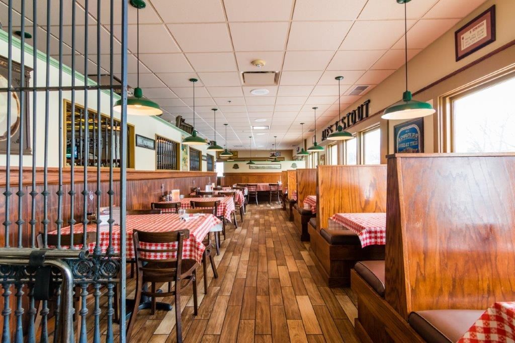 Restaurant interior with checkered tablecloths, wooden booths, and decorative lighting.