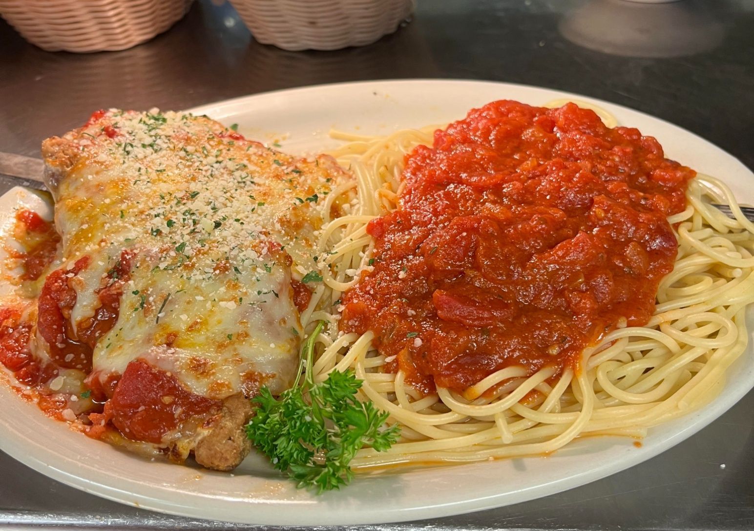 Chicken parmesan and spaghetti with red sauce on a white plate.
